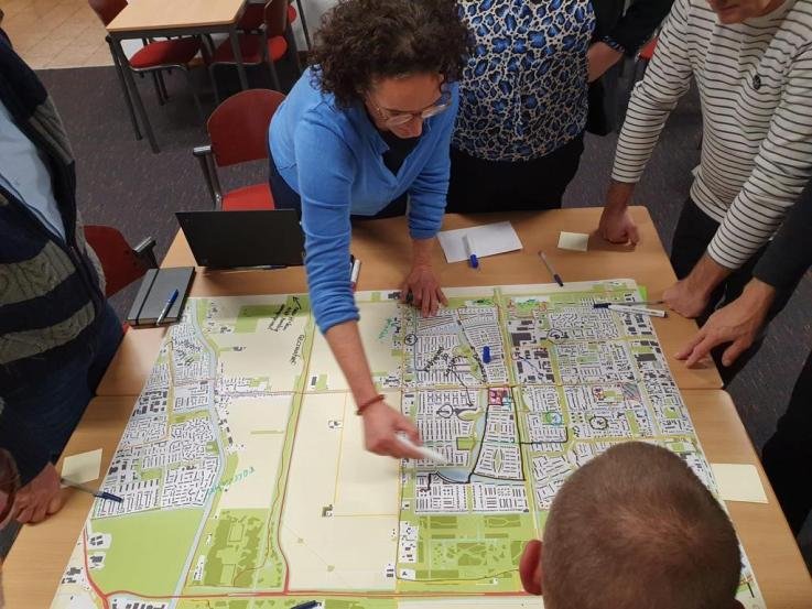 Foto: deelnemers van de werksessie buigen zich tijdens de bijeenkomst over de kaart, de plattegrond.