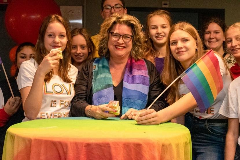 Afbeelding: foto van wethouder Marjolein Steffens met jongeren en de regenboogvlag