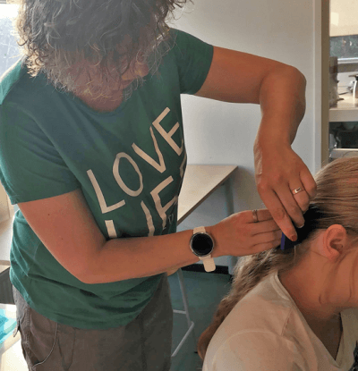 Afbeelding: foto van Mandy Kuijk met luizenkam, controleert een persoon op luizen