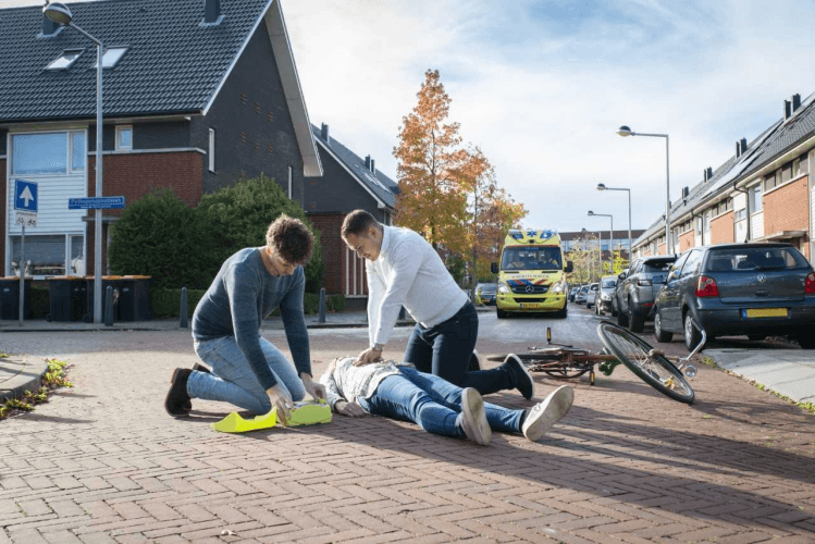 Afbeelding: foto van reconstructie reanimatie op straat, 2 mensen die slachtoffer hulp verlenen