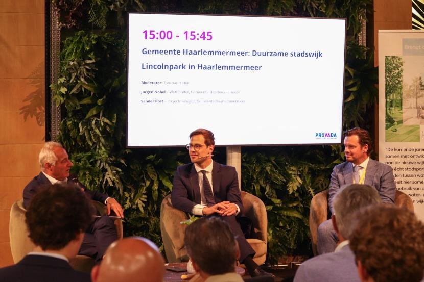 Presentator Tom van 't Hek in gesprek met wethouder Jurgen Nobel (Woningbouw) en projectmanager Sander Post