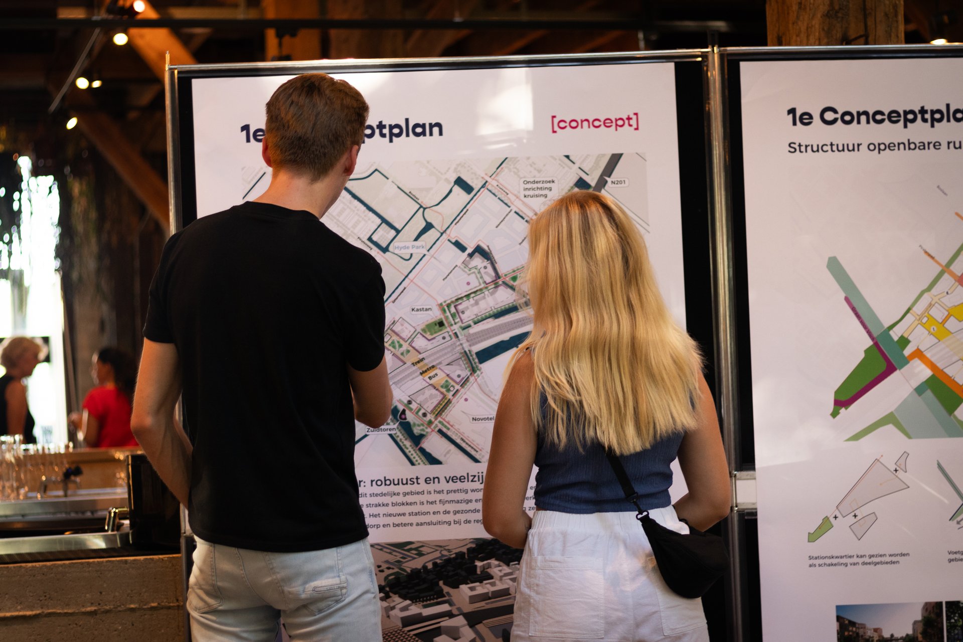 Bezoekers bekijken een informatieposter over Stationskwartier
