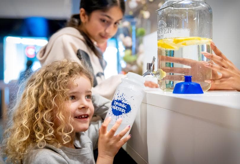 Afbeelding: foto van kinderen bij voorraadfles water met citroen