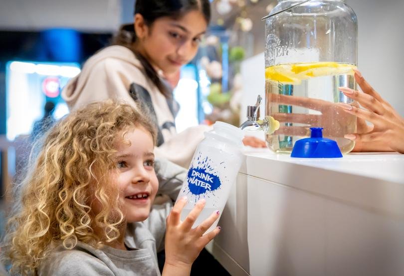 Afbeelding: foto van kinderen bij voorraadfles water met citroen