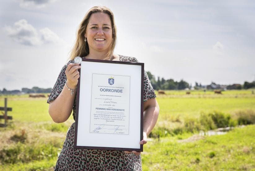 Afbeelding, foto van Laura Kroon met de Penning van Verdienste en bijbehorende oorkonde