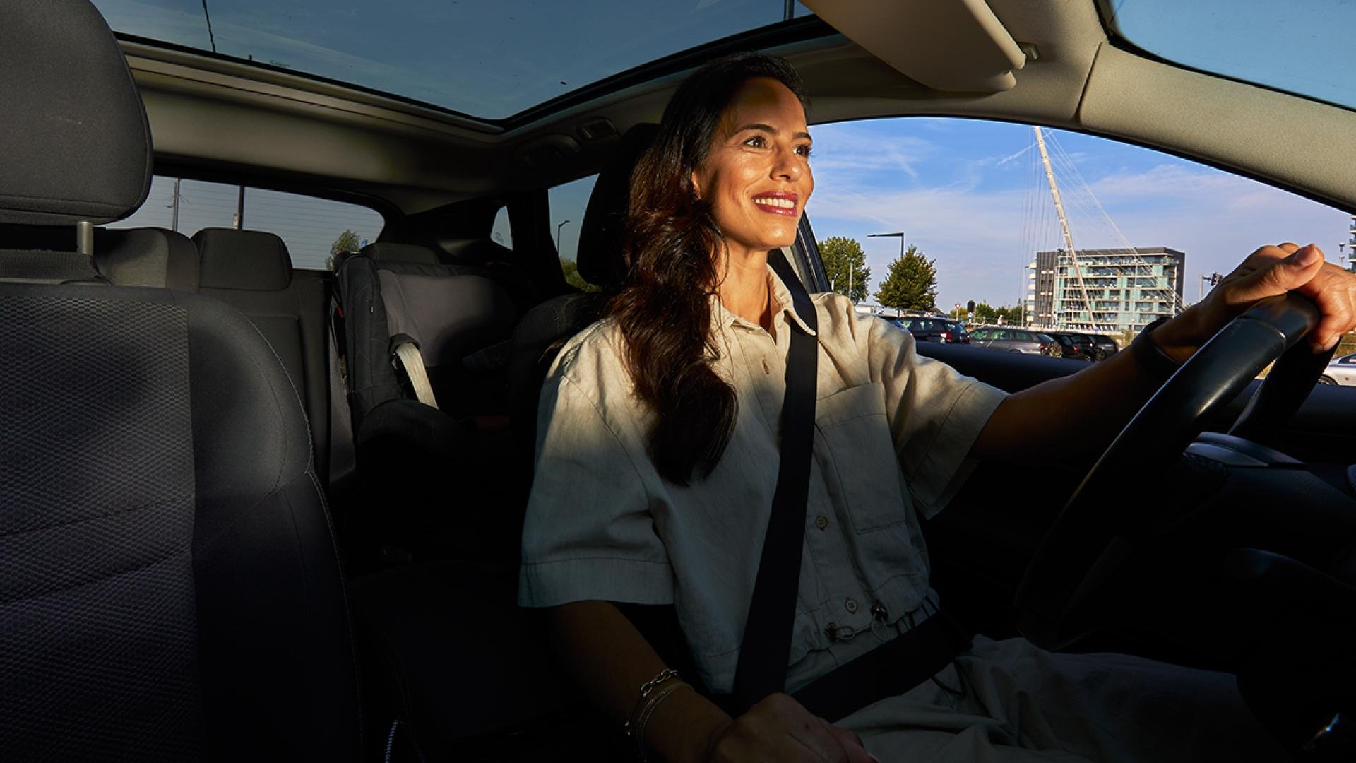 Een vrouw rijdt glimlachend Haarlemmermeer tegemoet. Ze is op weg naar haar nieuwe baan.