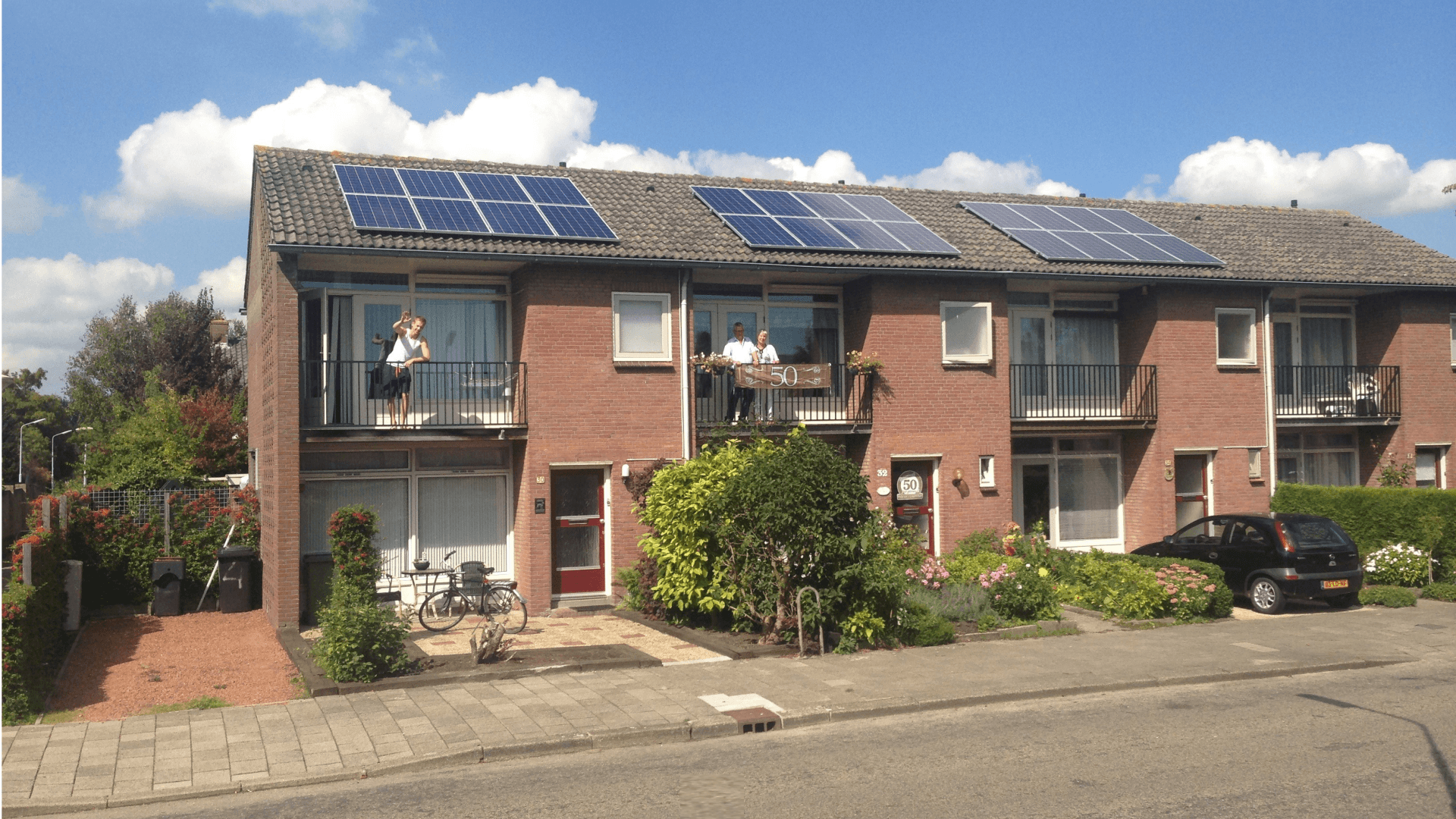 bewoners op balkon van rijtjeshuizen met zonnepanelen