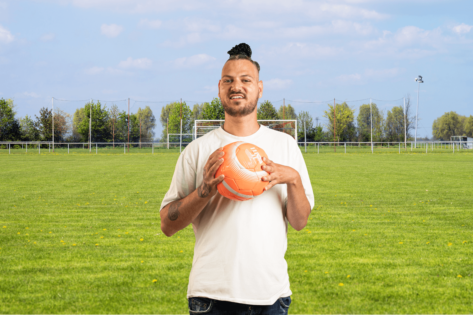 Ambassadeur Ian op een voetbalveld.