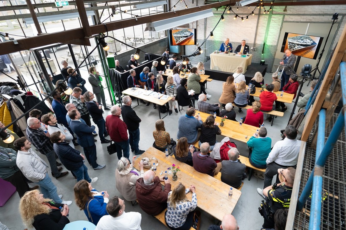 Volle vergaderzaal in SugarCity met aan de voorzitterstafel burgemeester Marianne Schuurmans en de griffier