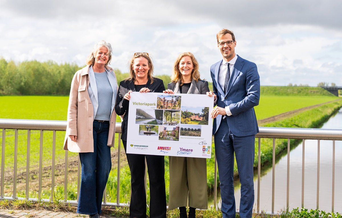 Vier mensen op een brug houden bord vast met daarop de tekst 'Victoriapark', foto's, logo's en handtekeningen