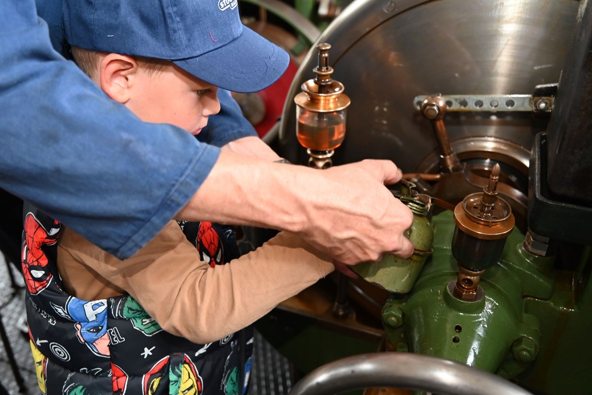 Een jongetje helpt een machinist bij het stoomgemaal Halfweg