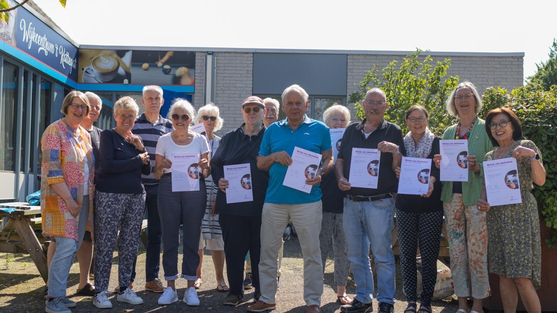 Groepsfoto van zo'n twintig mensen die een certificaat omhoog houden voor wijkcentrum t Kattegat 