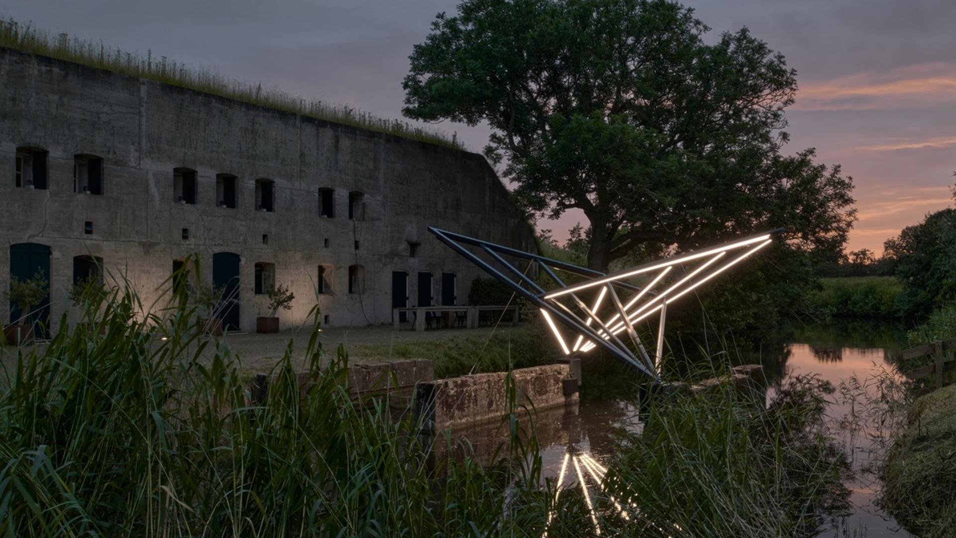 Het verlichte kunstwerk voor het Fort van Hoofddorp bij het vallen van de avond