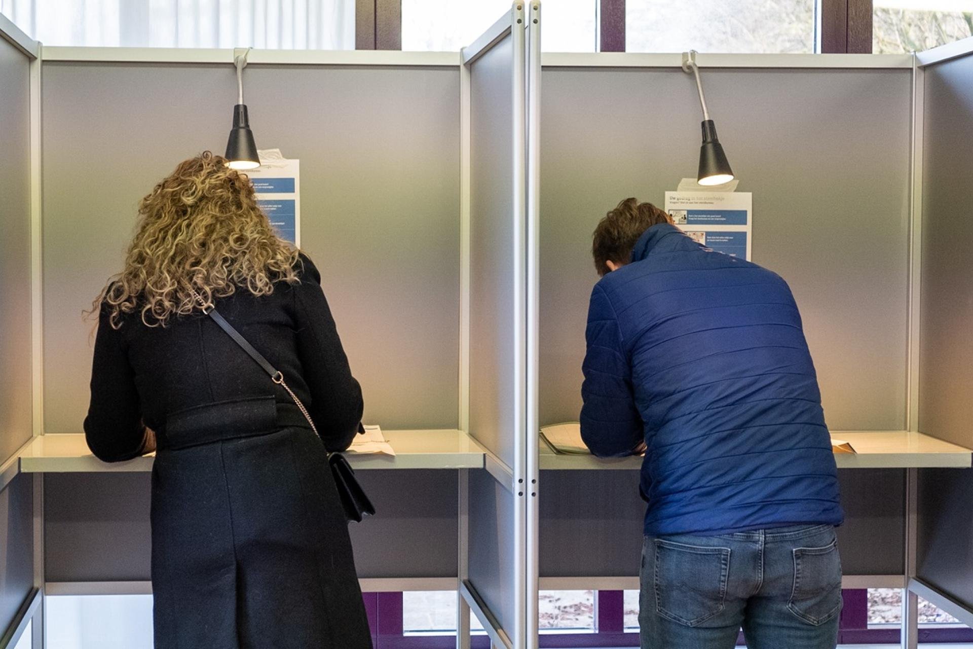 Twee kiezers in een stemhokje