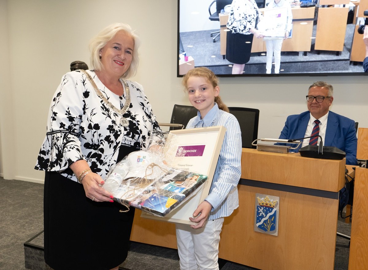Burgemeester Marianne Schuurmans overhandigt scheidend kinderburgemeester Vivienne een oorkonde en een feestelijk verpakt fotoboek