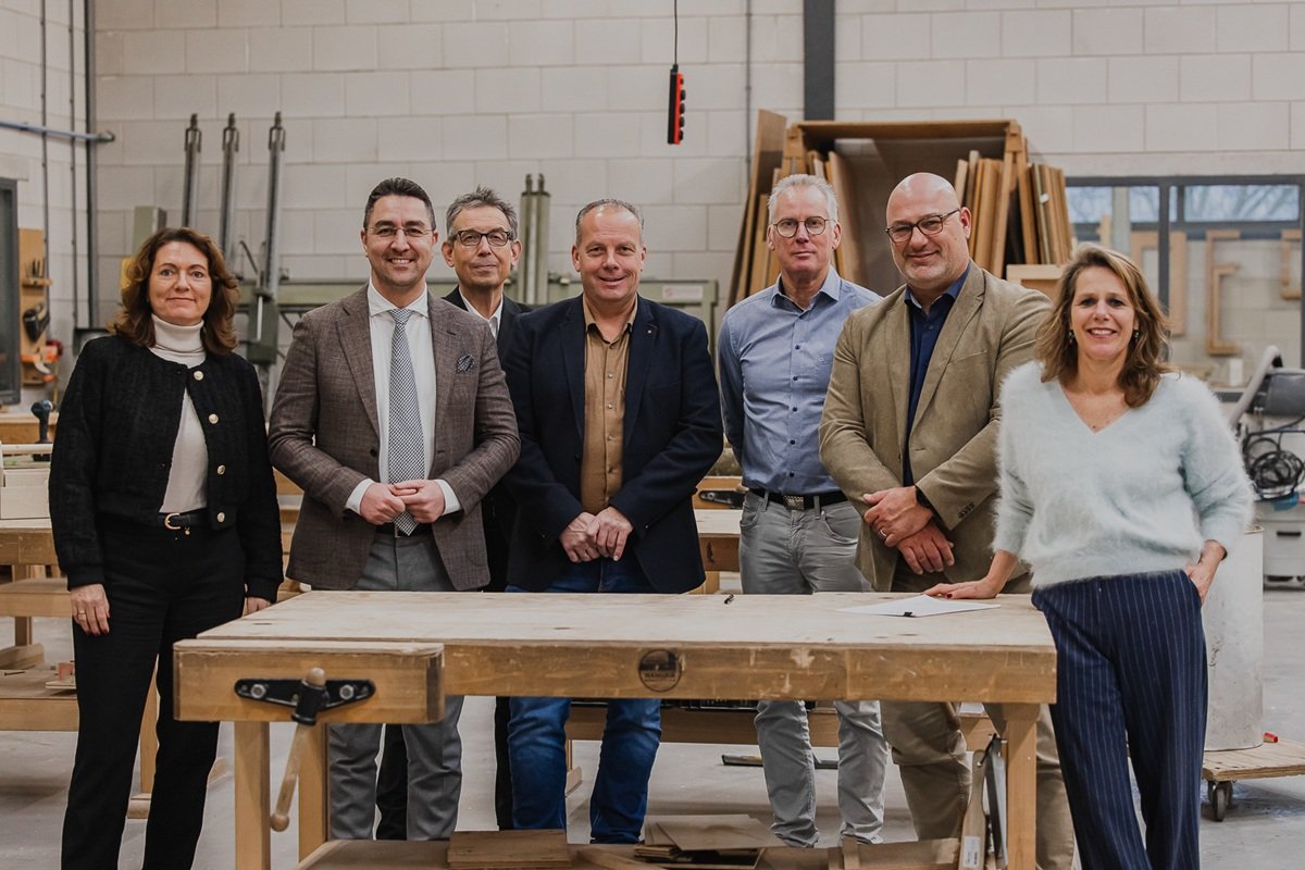 De ondertekenende partijen achter een werkbank