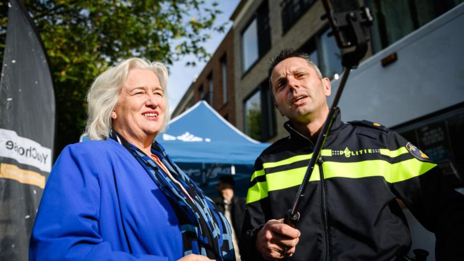 Burgemeester Marianne Schuurmans en een politieagent maken een selfie op straat.
