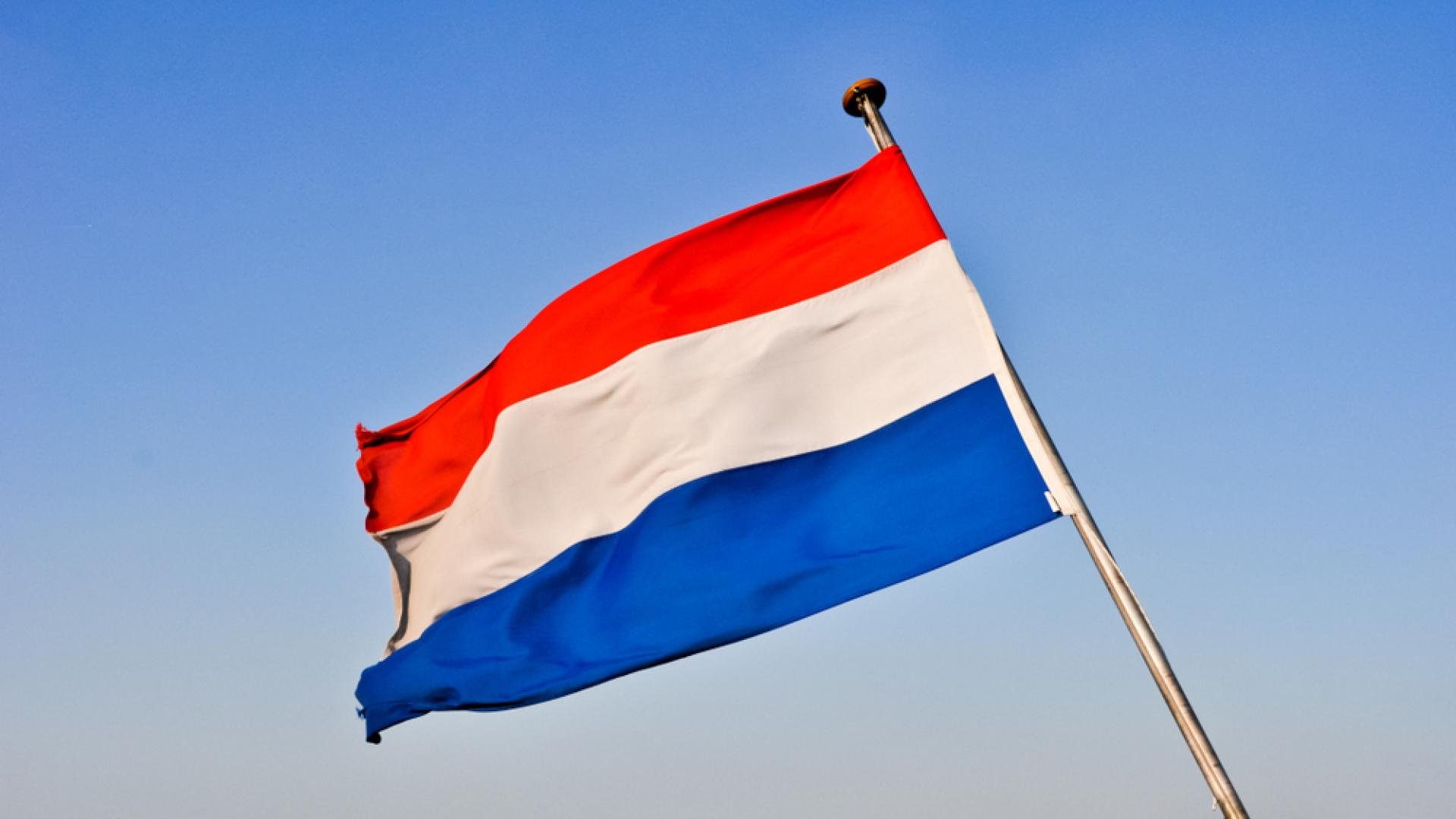 De Nederlandse vlag met op de achtergrond een blauwe lucht